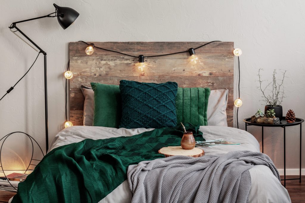 A comfortable bedroom with soft green and grey blankets and pillows.